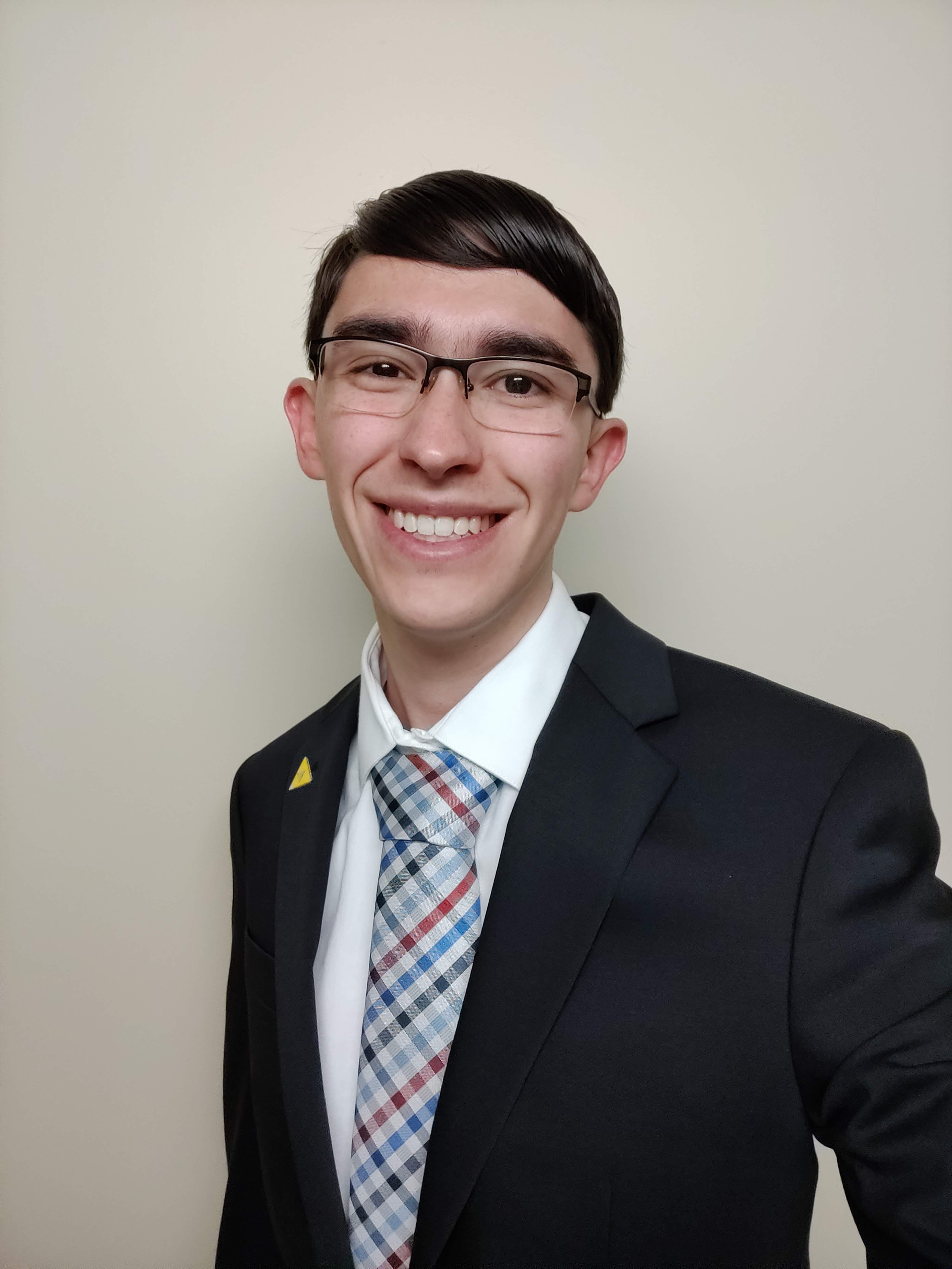 A picture of Daniel in a suit against a plain background.